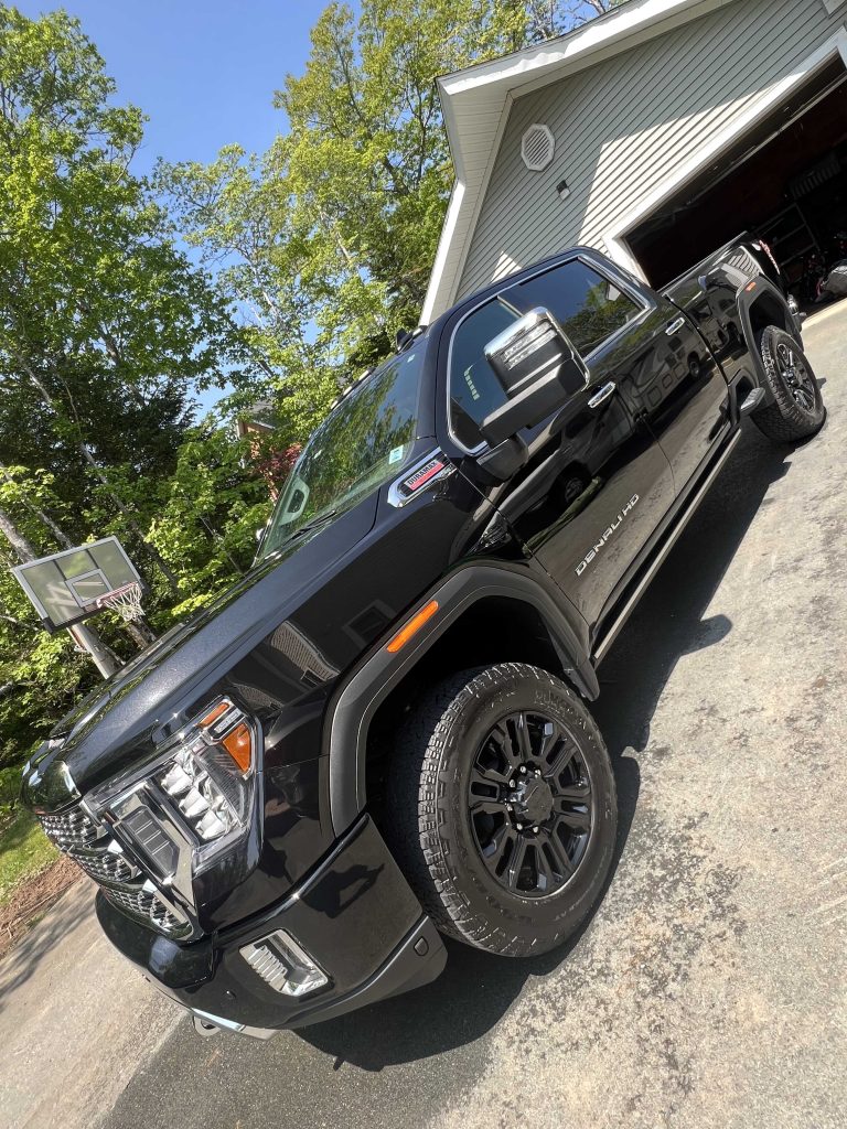 Black Denali HD pickup with mirror-like paint after paint correction, parked on a driveway.| none | swirl removal | machine polishing | clear coat refinement