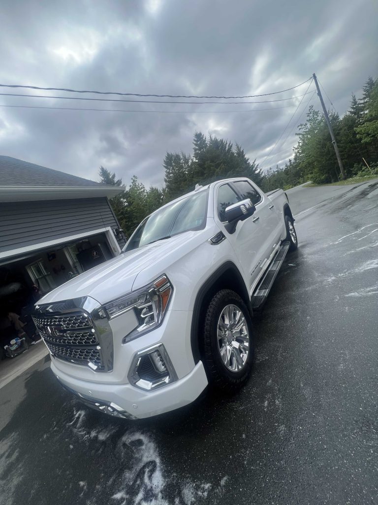 White GMC pickup with glossy paint and clean wheels after paint correction, parked on wet pavement.| none | swirl removal | machine polishing | clear coat refinement