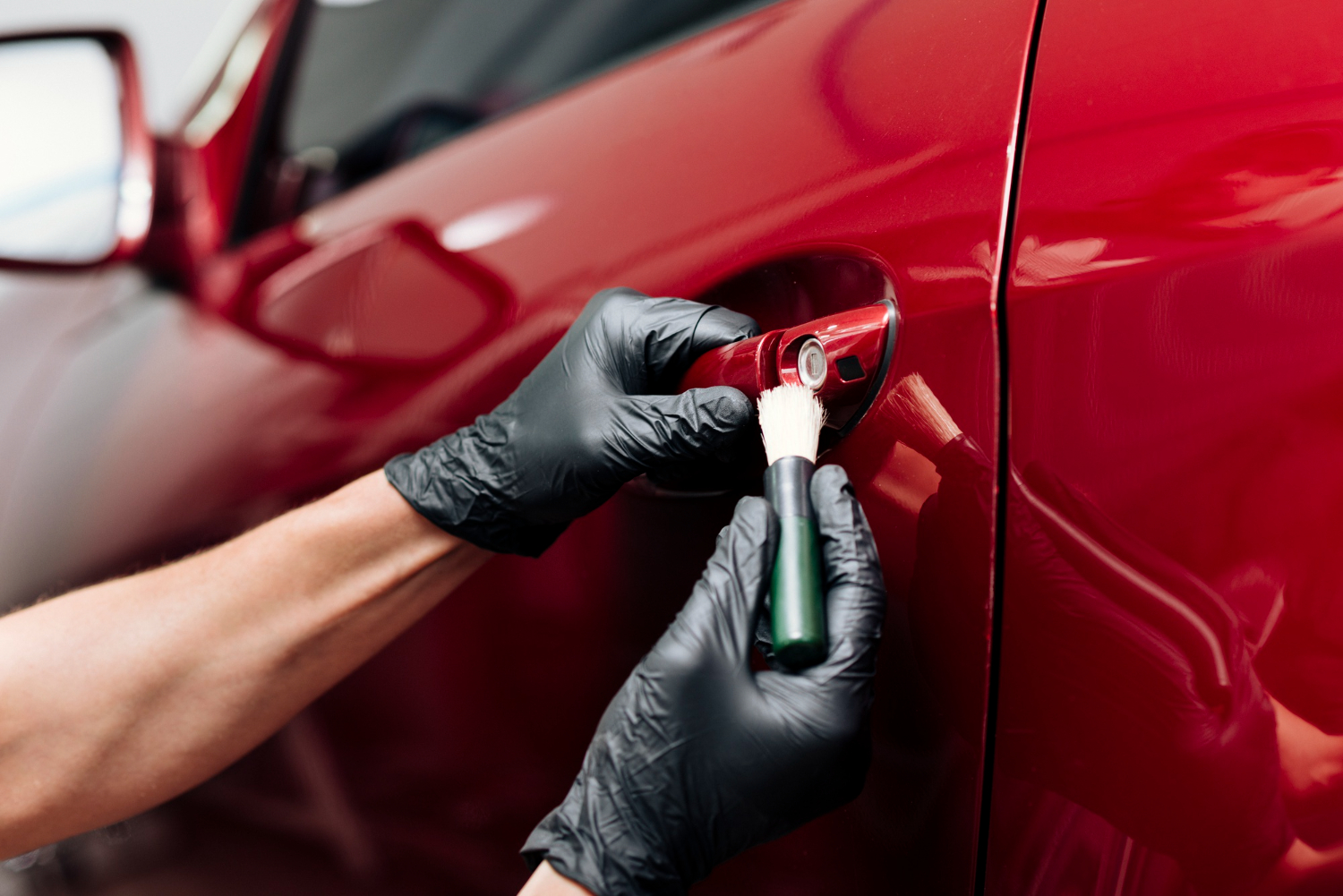 Gloved technician applies ceramic coating to a red car hood in Dartmouth under bright shop lights.| Halifax Harbour | paint prep | decontamination wash | hydrophobic protection